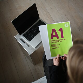 Blick von oben auf eine Deutschlehrerin, die eine Goethe-Prüfung A1 Jugendliche in der Hand hält.