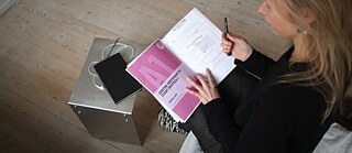 Blick von oben auf eine Deutschlehrerin, die eine Goethe-Prüfung A1 in der Hand hält.