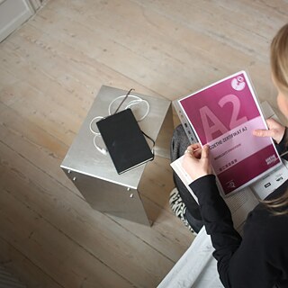 Blick von oben auf eine Deutschlehrerin, die eine Goethe-Prüfung A2 in der Hand hält.