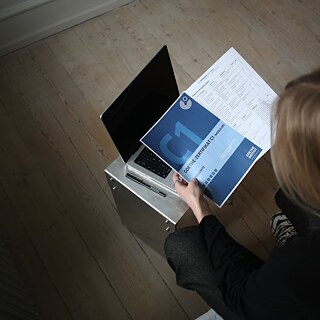 Blick von oben auf eine Deutschlehrerin, die eine Goethe-Prüfung C1 in der Hand hält.