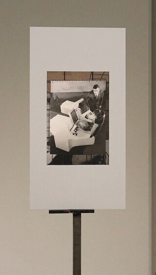 Das Kunstwerk von Johanna Gonschorek besteht aus einem Foto, das in eine klare Acrylglasstruktur integriert ist und von einem schlichten Metallständer getragen wird. 