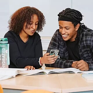 Three students work together in the classroom with learning materials.
