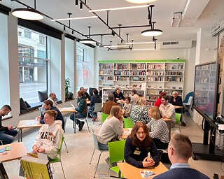 Foto von Menschen, die jeweils zu zweit an einem Tisch sitzen und reden