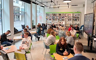 Foto von Menschen, die jeweils zu zweit an einem Tisch sitzen und reden