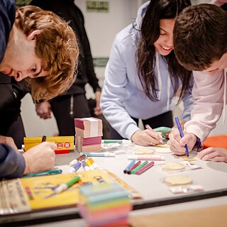 Die Schüler einer Grundschule sitzen im Klassenraum und verfolgen den Unterricht. Ein Mädchen hält ein Tablet in den Händen.