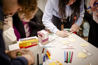 Uma menina e um menino escrevem sua palavra favorita em alemão num pedaço de papel.