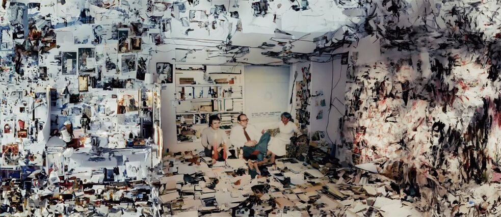 Drei Personen in einem Raum, der von Dokumenten, Fotos und Büchern übersät ist