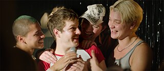 Eine Party: ein junger Mann ist umringt von seinen Freunden