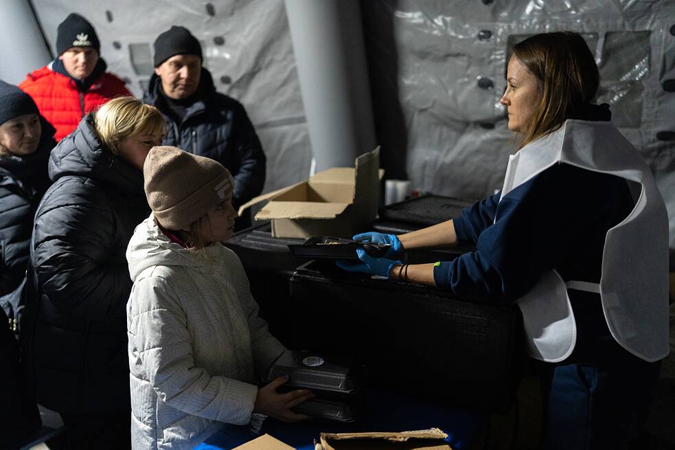 Freiwillige der Organisation World Central Kitchen verteilen Banosh mit Fleisch und heißen Borschtsch.
