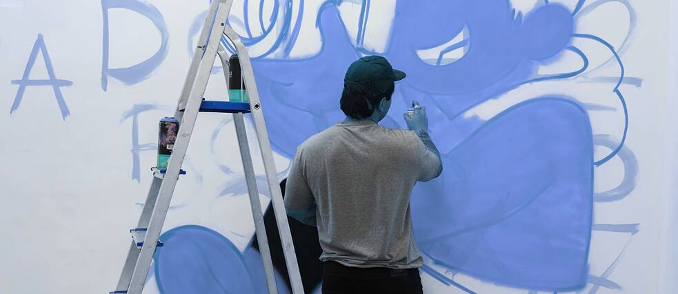 Street artist creating a mural on an urban wall