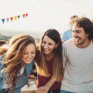 Lachende und tanzende junge Leute bei einer Dach-Party.