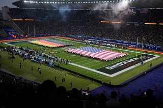 Deutschlandflagge und US-Flagge ausgerollt auf einem Football-Spielfeld.