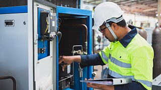 Ein Elektrotechniker bei der Arbeit an einem Gerät. 