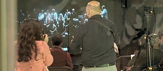 From the first performance in Delhi, with the audience in Bonn visible as a live projection in the background.