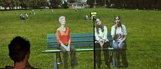 Actors from Delhi and Bonn projected onto a shared screen during the Delhi performance, using green screen, live cameras, and projectors in both locations.