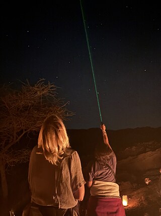 Zwei Teilnehmer zeigen mit dem Laser in einer Sternbeobachtungsnacht auf die Sterne.