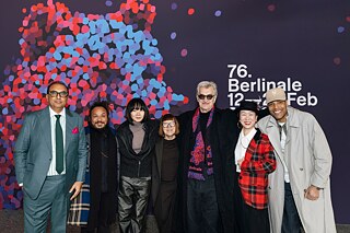 Die internationale Jury 2026: (v.l.n.r.) Shivendra Singh Dungarpur, Min Bahadur Bham, Bae Doona, Ewa Puszczyńska, Wim Wenders, HIKARI, Reinaldo Marcus Green 