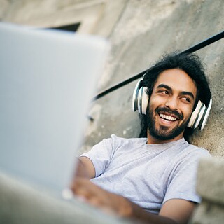 Mann mit Kopfhörer und Laptop