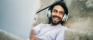 Mann mit Kopfhörer und Laptop