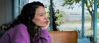 Junge Frau mit langem lockigem Haar in rosa Pullover im Profil 