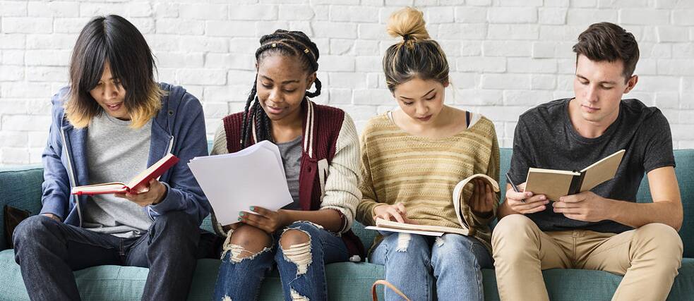 Mehrere junge Schüler sitzen nebeneinander auf einem Sofa und lesen. Die Bilder der Serie "JUNGE LERNENDE" zeigen Gruppen von jungen Lernenden – Kinder und Jugendliche -, die Spaß an Bildung, Lernen und an der deutsche Sprache vermitteln sollen.