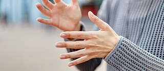 Eine Person streckt ihre Hände nach vorne, um eine Botschaft mit Gebärdensprache zu vermitteln.