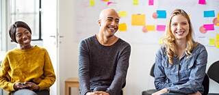 Junge Unternehmer:innen in einer Besprechung, sie lachen.