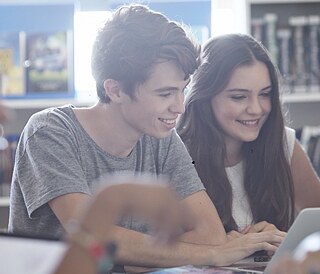 Zwei Jugendliche sitzen während einer Wiederholungswoche für Jugendliche gemeinsam an einem Tisch und arbeiten konzentriert an Lernmaterialien in einer hellen Unterrichtsumgebung.