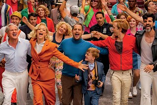 Standbild aus „Ich war noch niemals in NY“ (2019) zeigt eine freudige sehr bunte Gruppe der Reisenden tanzend in der Straße. Basierend auf dem gleichnamigen Musical von Stage Entertainment verfilmte Regisseur Philipp Stölzl den Stoff einer ungewöhnlichen Kreuzfahrt und lässt die Songs des beliebten deutschen Komponisten und Musikers Udo Jürgens wieder aufleben.