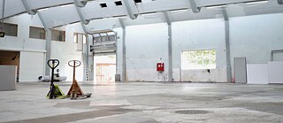 Zwei Hubwagen stehen in einer leeren Fabrikhalle, die zu Fabrikken for kunst og design gehören.