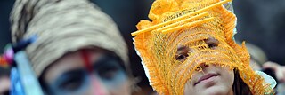 Zwei junge Frauen demonstrieren bei der Fashion Week Berlin für soziale, ökologische und faire Kleidung. Sie tragen phantasievolle, selbst gestaltete Kopfbedeckungen aus Gemüse-Netzen.