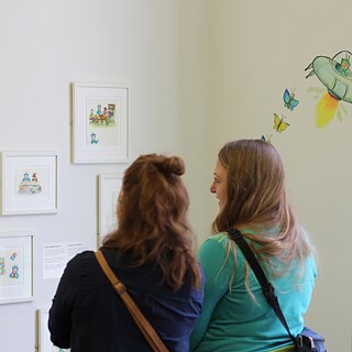 Besucherinnen sehen sich die Zeichnungen von Axel Scheffler in der Ausstellung an