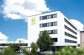 Fünfstöckiges weißes Gebäude mit dem grünen Logo des Goethe-Instituts