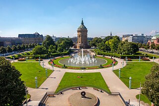 Im Vordergrund ein großer Park mit Fontäne, im Hintergrund in der Mitte ein Wasserturm