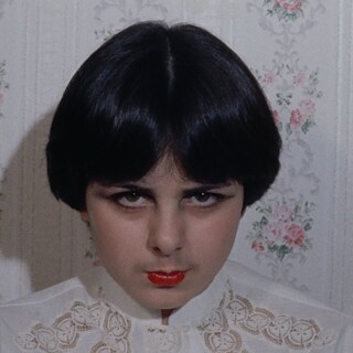 close up of young white woman with black hair weathing bright red lipstick and looking into the camera