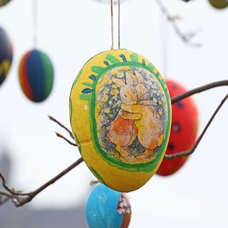 Dekorierte Ostereier hängen von Ästen herab.