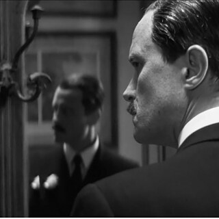 Filmstill fra "Das Verschwinden des Josef Mengele". August Diehl som Josef Mengele set bagfra, hans profil ses i spejlet. 