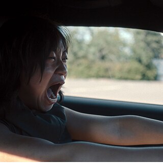 Filmstill fra "Staatsschutz": En kvinde sidder skrigende bag rattet i en bil.