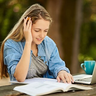 אישה לומדת בחוץ עם מחשב נייד וספר