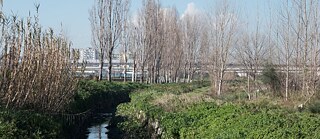 Landschaft mit Wasserkanal vor Schnellstraße und Hochhäusern