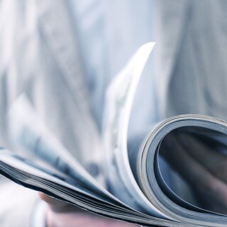 The upper body of a person holding a magazine.. 