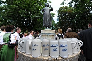 Bierkrüge mit der Aufschrift "Münchner Bier" am Liesl-Karlstadt-Brunnen auf dem Viktualienmarkt.
