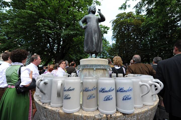 Bierkrüge mit der Aufschrift "Münchner Bier" am Liesl-Karlstadt-Brunnen auf dem Viktualienmarkt.