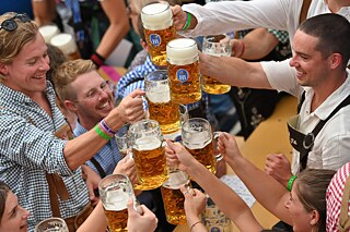 Besucher des Oktoberfests feiern und prosten sich mit Bierkrügen zu.