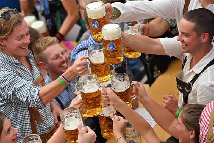 Besucher des Oktoberfests feiern und prosten sich mit Bierkrügen zu.