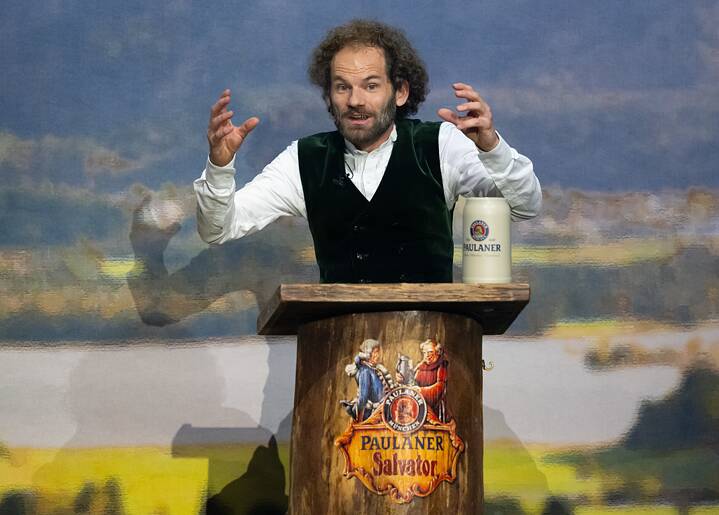 Maximilian Schafroth, Schauspieler und Kabarettist, hält beim Starkbieranstich auf dem Nockherberg die Fastenpredigt mit einem Krug Salvator-Bier vor sich stehend.
