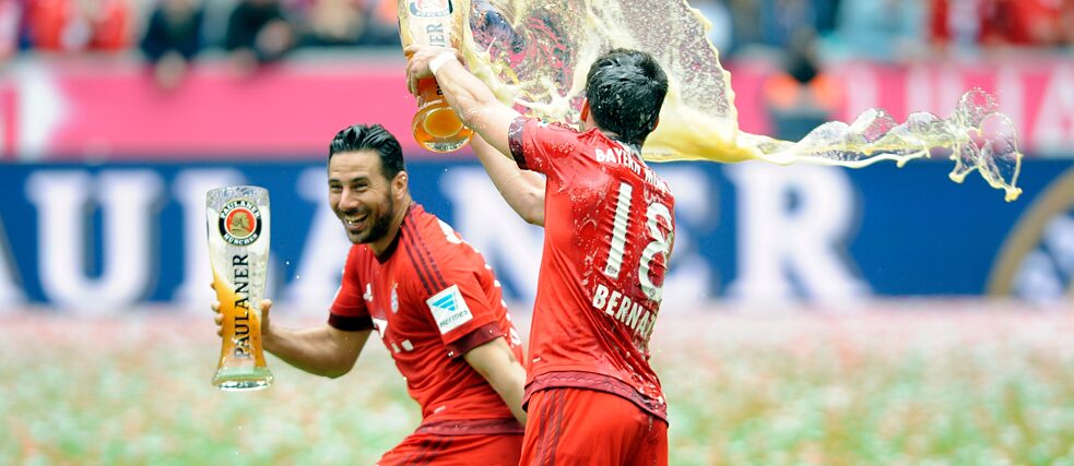 Ein Fußballspieler vom FC Bayern München schüttet feierlich Bier auf seinen Mitspieler.