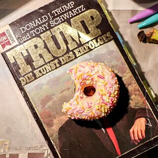 Na stole leží kniha a na její titulní stránce donut.