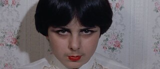 close up of young white woman withe black hair weathing bright red lipstick and looking into the camera