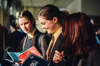 Several young students sitting around a table reading information material.